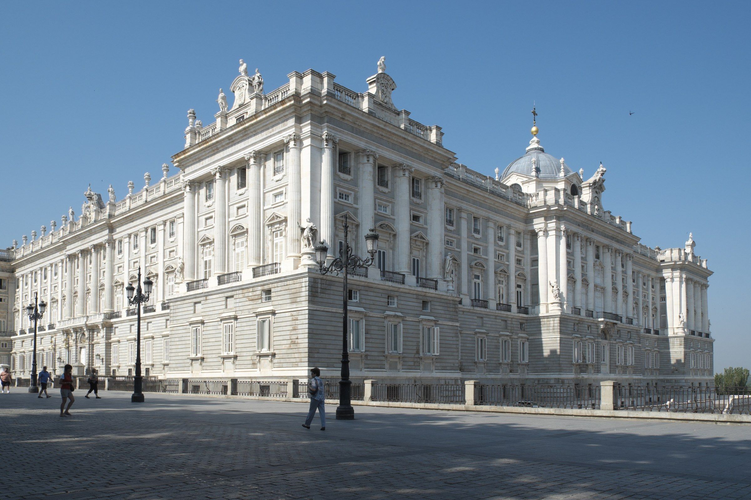 Main facade of the Royal Palace of Madrid, with its limestone columns under a clear blue sky