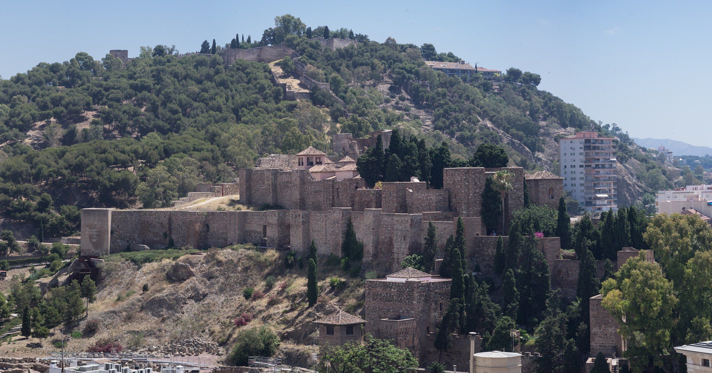 The Moorish fortress of the Alcazaba of Málaga on the hillside, with the city visible behind it under a clear sky