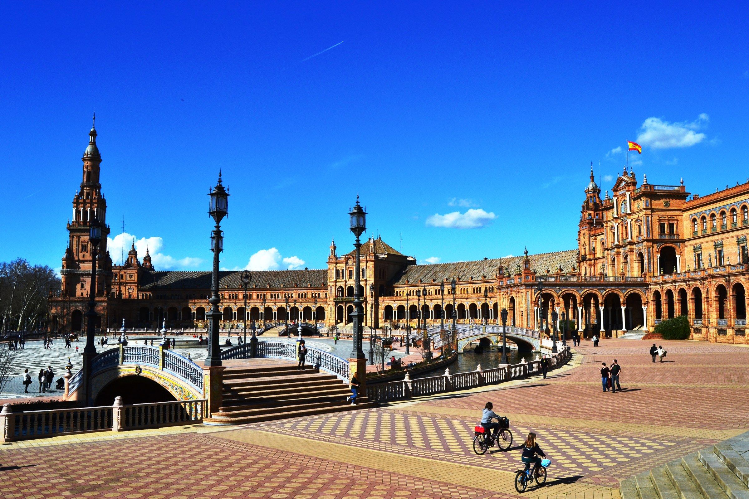 Plaza de España in Seville with its canal and ceramic-tiled bridges under a clear blue sky